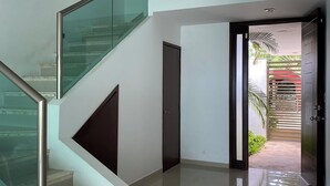 A modern interior with a glass railing staircase, a door leading to a covered outdoor area, and a tiled floor. - Beautiful comfortable home with swimming pool (Mérida)
