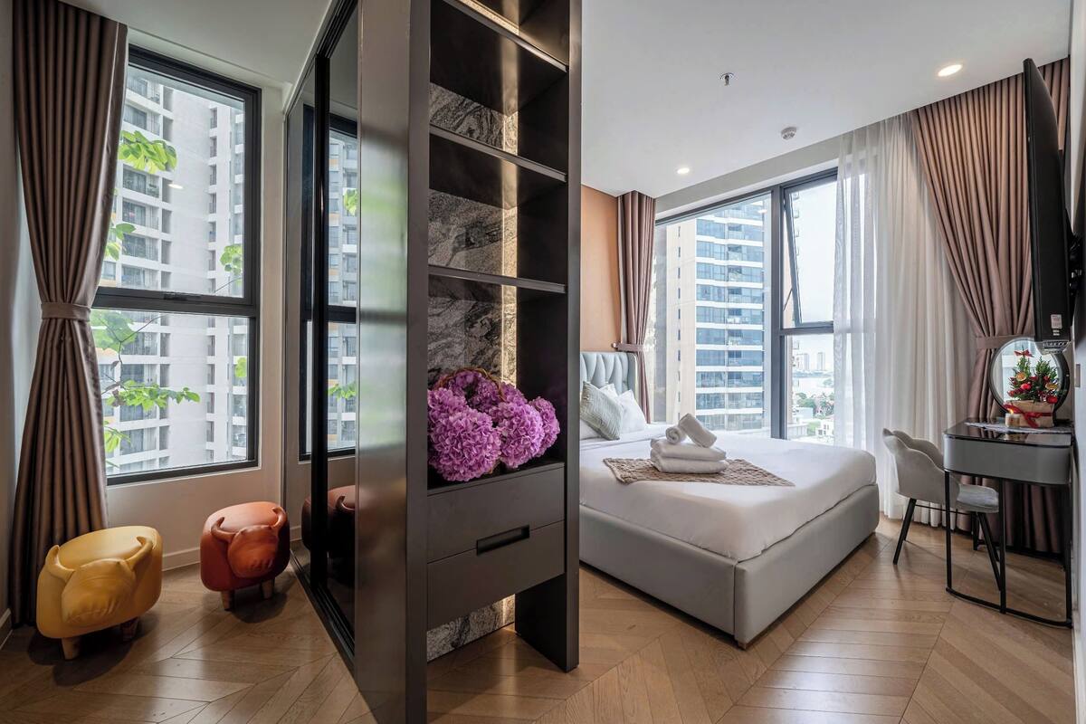 A modern hotel room with a large bed, a desk, and a wardrobe.