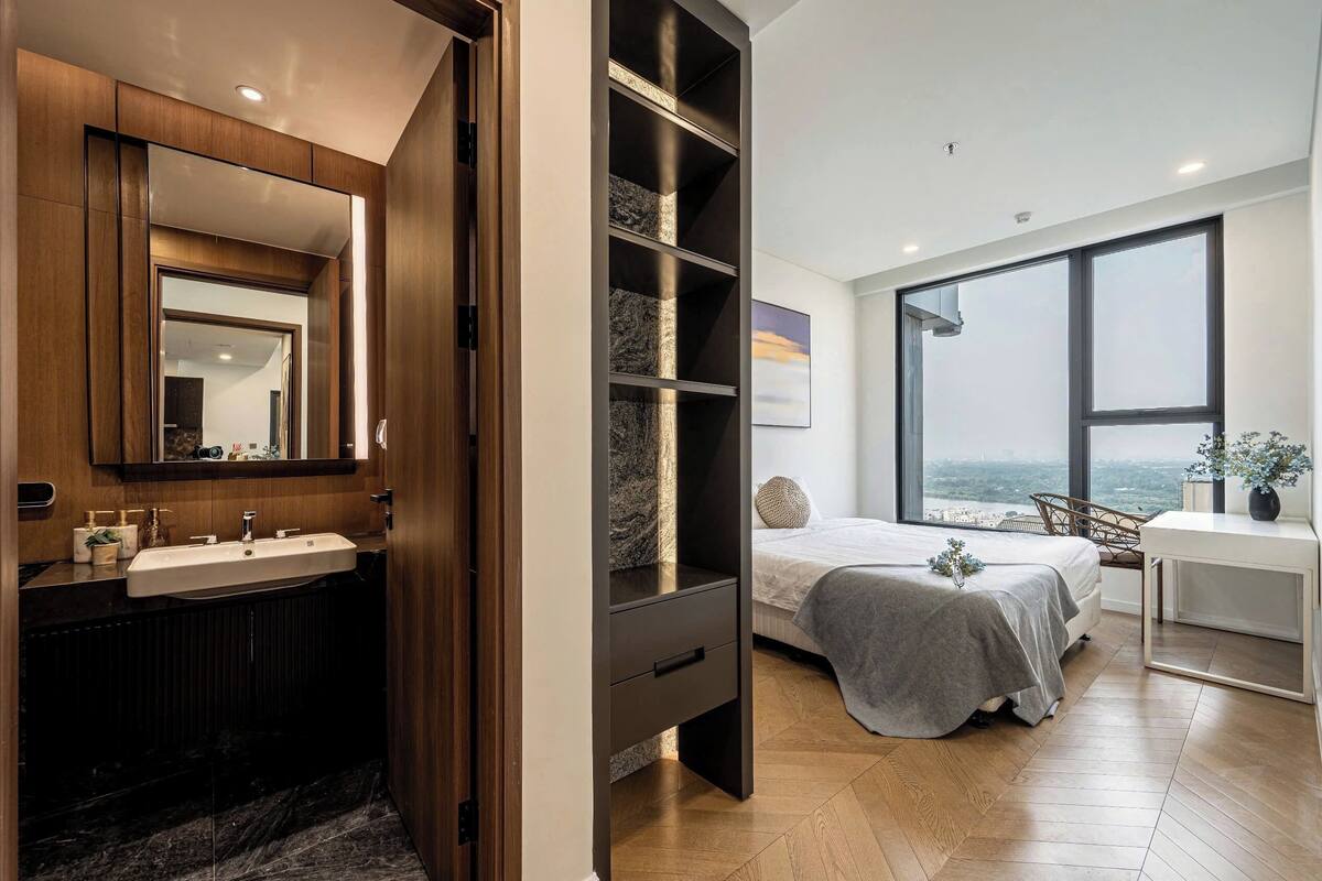 A modern bedroom with a large window, a built-in wardrobe, and a bedside table.