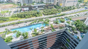 A high-rise hotel with a rooftop pool, lush greenery, and a busy street below. - LUMIERE Riverside Signature Residence (Ho Chi Minh City)