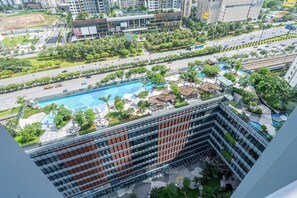 A high-rise hotel with a rooftop pool, lush greenery, and a busy street below. - LUMIERE Riverside Signature Residence (An Phu)