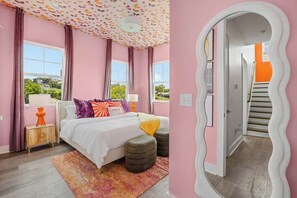 Ein Schlafzimmer mit Bett, Nachttischen, einem Spiegel und Blick ins Freie.