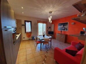 A compact living space with a kitchen, dining area, and a red sofa. - Cozy apartment 5 minutes from the beach with private parking (Brenzone sul Garda)