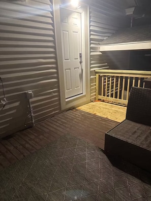 Una habitación con terraza de madera, una puerta y un pequeño banco de madera.