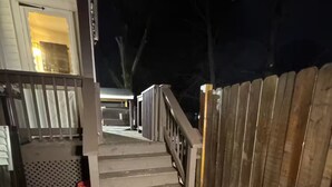 A wooden deck with a metal railing leading to a covered area. - Private Suite w/ Bath & Free Parking (Brockton)
