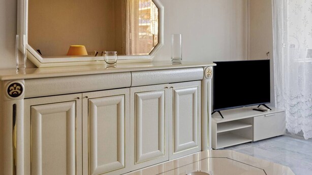 Een moderne woonkamer met een grote spiegel, een flatscreen televisie en een glazen salontafel.