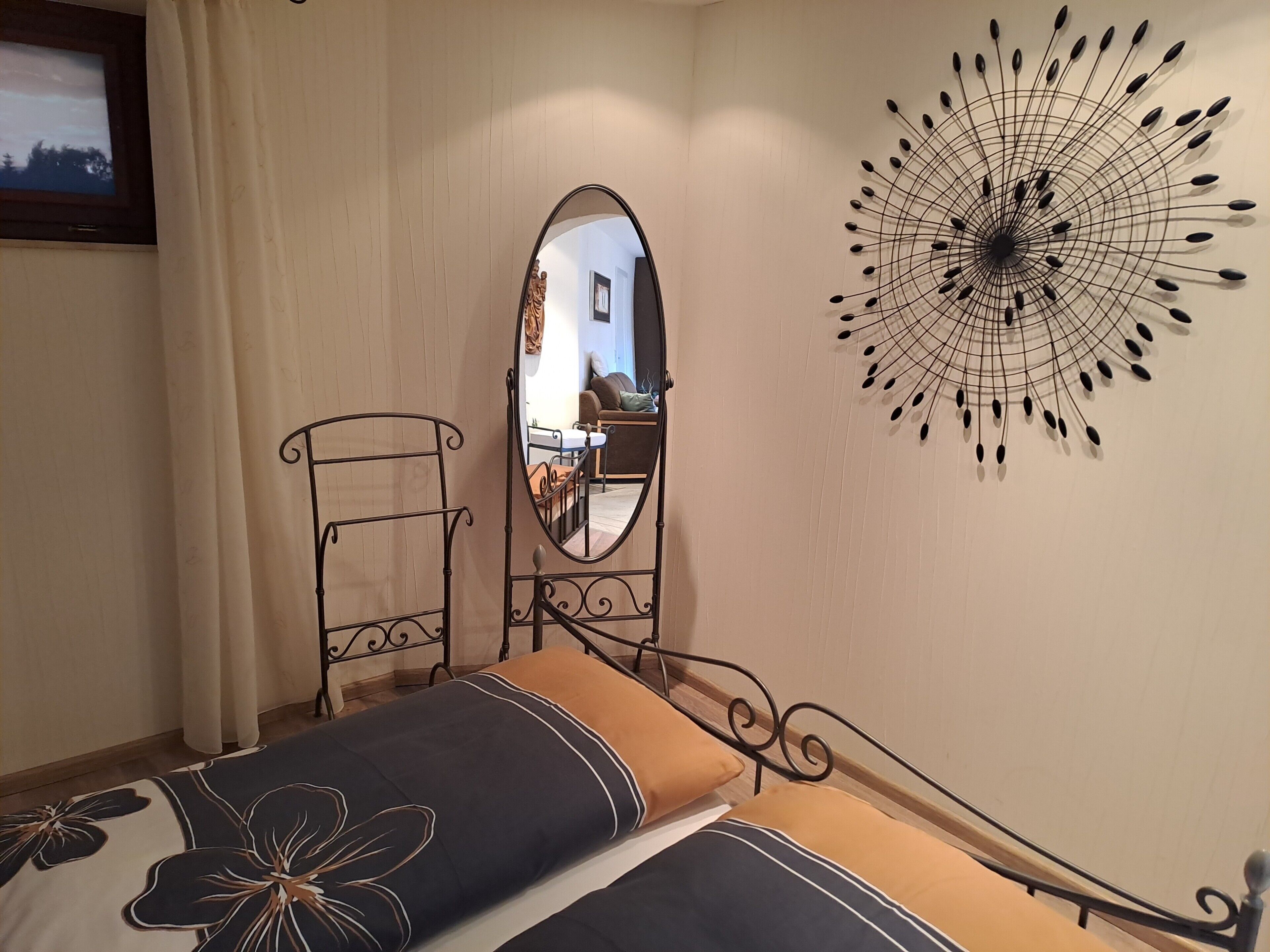 Ein Schlafzimmer mit einem Bett, einem Spiegel, einem Wandbild und einem Fernseher an der Wand.