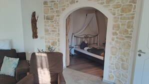 A room with a stone wall, a bed with a canopy, a sofa, and a chair.