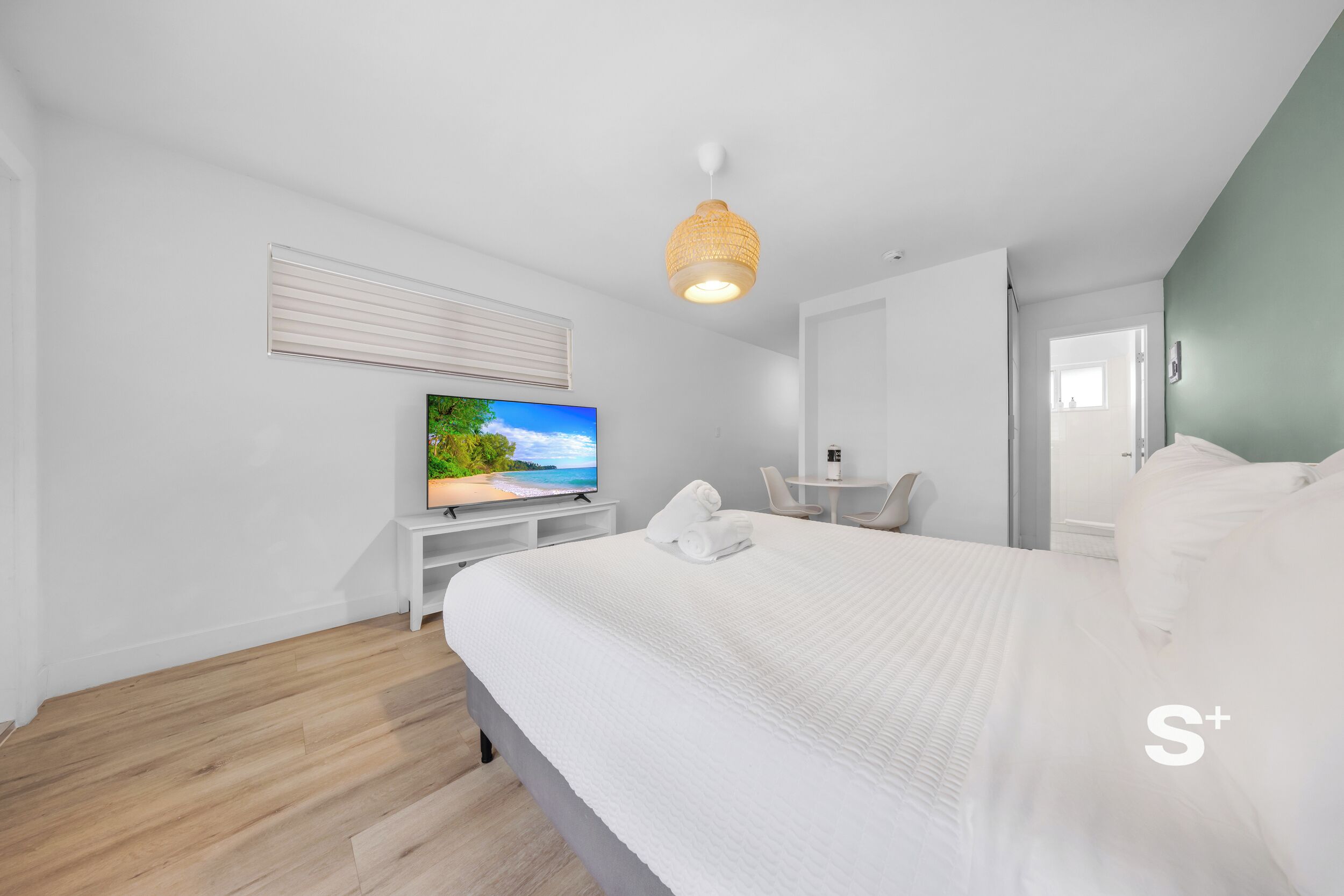 A modern hotel room with a large bed, a television, a small table, and a chair.