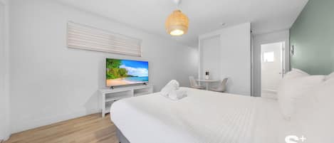 A modern hotel room with a large bed, a television, a small table, and a chair.