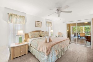 A bedroom with a bed, nightstands, a ceiling fan, and a view of the outdoors. - Villa Seastar - Cape Coral (Cape Coral)
