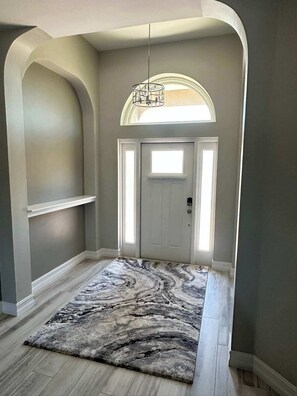 A hallway with a marble-patterned rug, a white door, and a hanging light fixture. - Villa Crystal Breeze (Cape Coral)