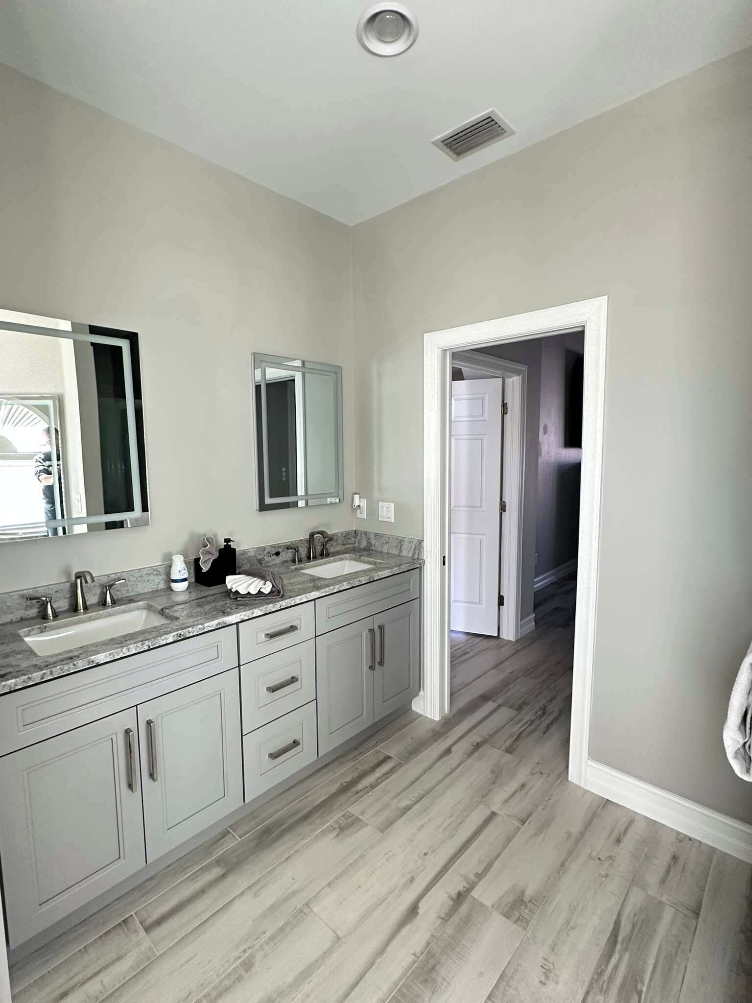 Un baño moderno con dos lavamanos, un espejo grande y una ducha a ras de suelo.