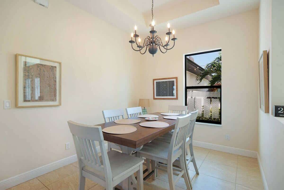 Une salle à manger agrémentée d’un lustre, d’une grande fenêtre et d’œuvres d’art encadrées aux murs.