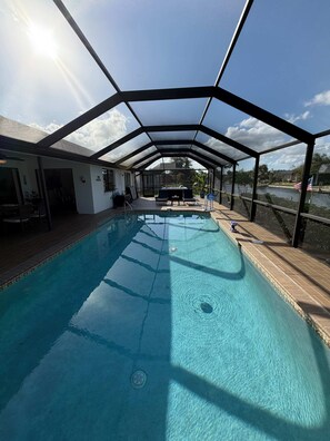 Ein überdachter Pool mit Blick auf einen See und ein Haus im Hintergrund.