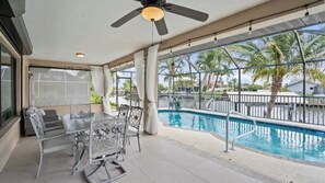 Ein überdachter Außenbereich mit Pool, Sitzgelegenheiten und Deckenventilator.