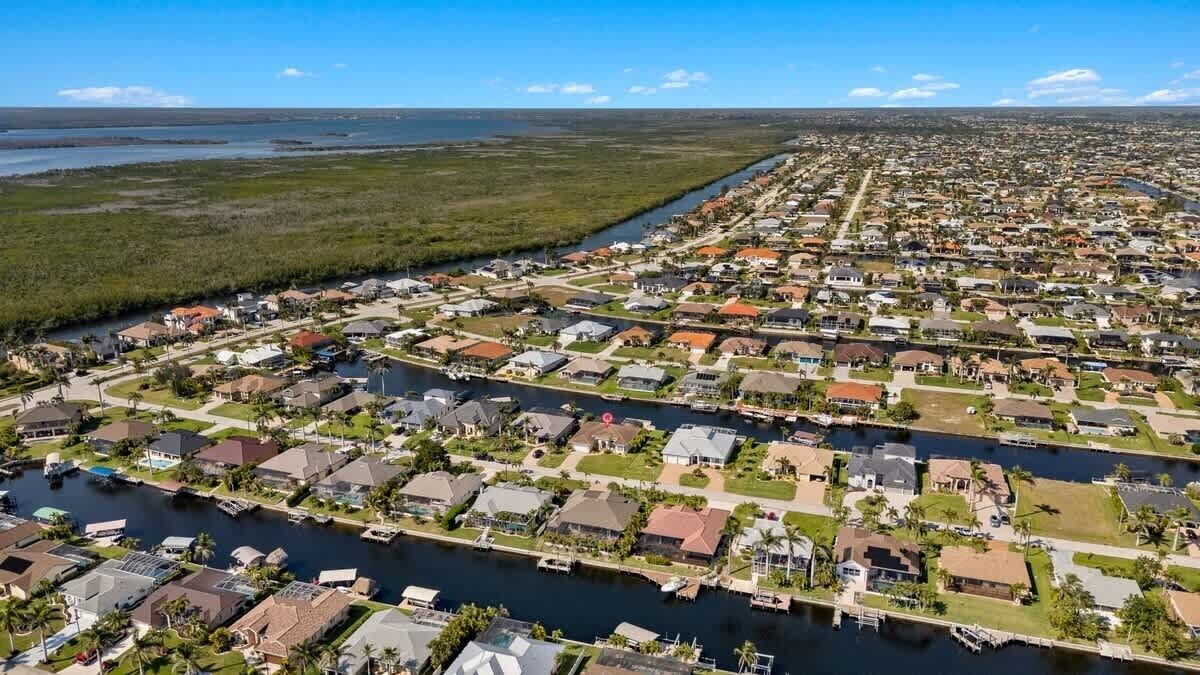 An aerial view of a residential area with houses, a river, and a marina.