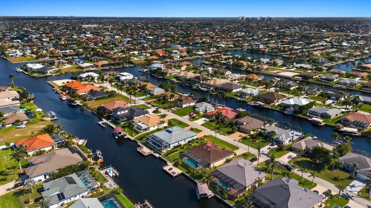 An aerial view of a residential area with houses, a marina, and a river.