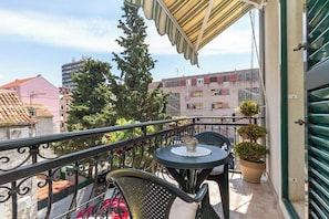 A balcony with a table and chairs, a potted plant, and a view of buildings. - Villa Split Art - Pistacio apt (Split)