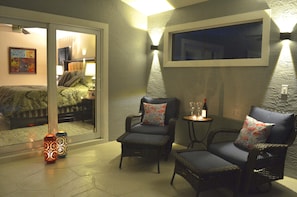 Ein gemütliches Zimmer mit Korbsesseln, einem kleinen Tisch mit Flasche und Gläsern sowie einem großen Fenster.