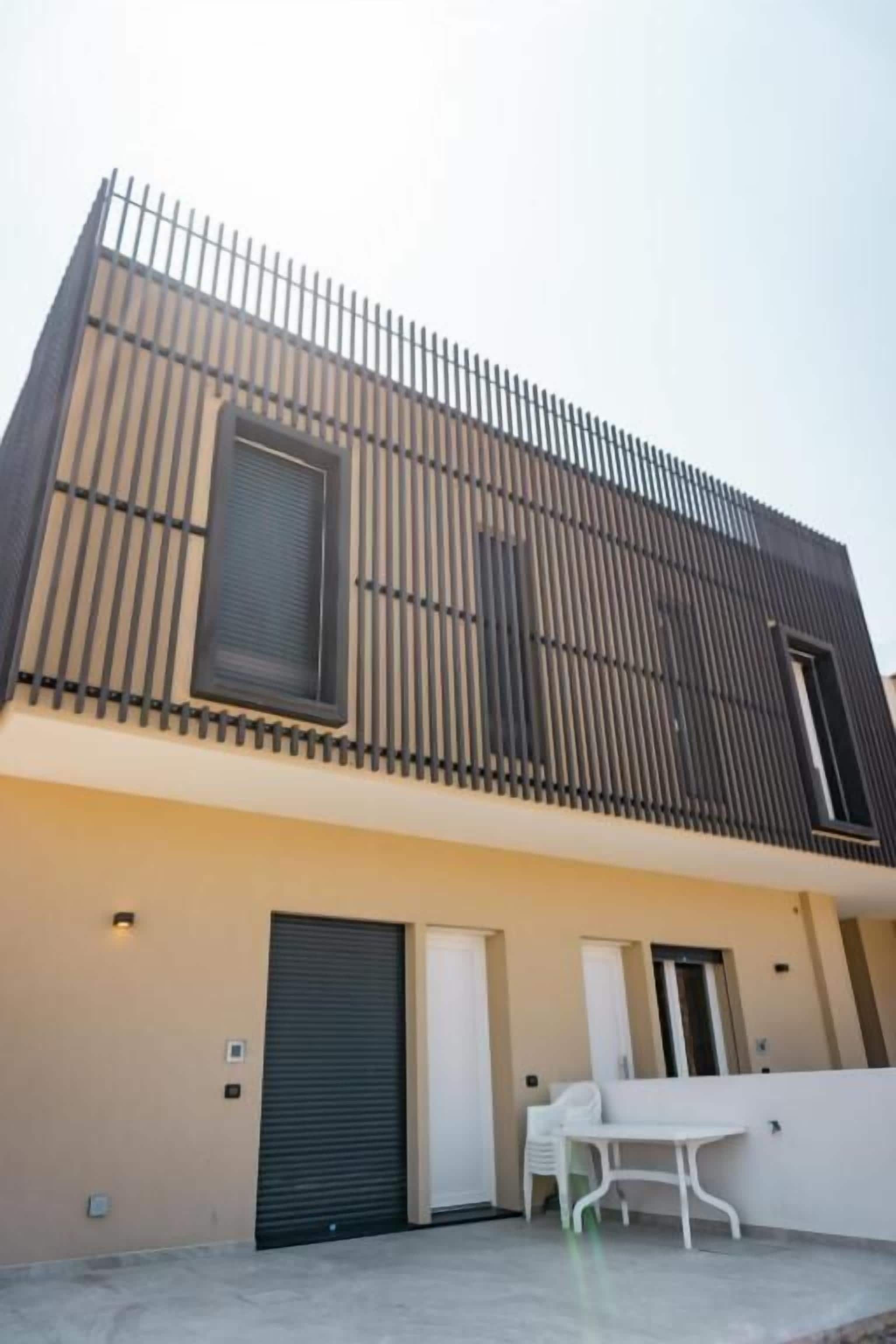 A modern building with a flat roof, a large window, and a gated entrance.
