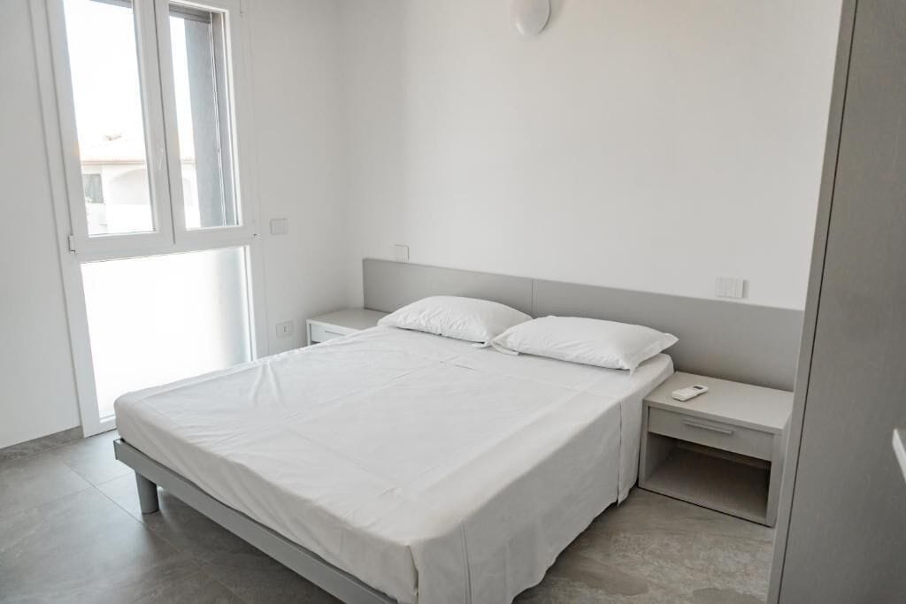 A minimalist bedroom with a large bed, bedside tables, and a window.