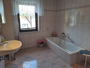 Un baño con lavabo, ventana y bañera.