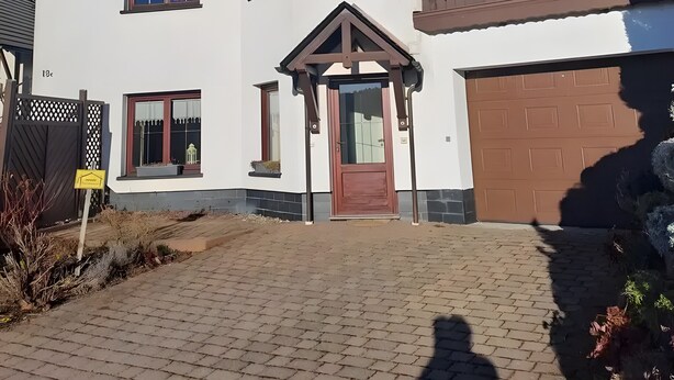 Ein zweistöckiges Haus mit brauner Tür, zahlreichen Fenstern und einer Garage.