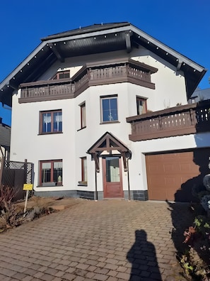 Una casa de dos pisos con una puerta marrón, varias ventanas y un garaje.
