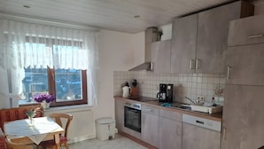 Eine Küche mit Esstisch, Stühlen, einer Kaffeemaschine und einem Kühlschrank.