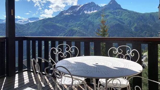 Ein Balkon mit Tisch und Stühlen mit Blick auf eine Berglandschaft.