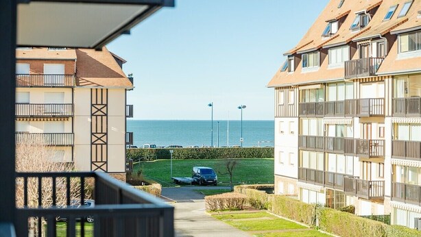 Vista di una zona residenziale con un sentiero che conduce a uno specchio d'acqua, circondata da palazzi con balconi.