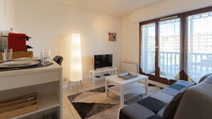 Un soggiorno con divano, tavolino, televisore e zona pranzo con tavolo e sedie.