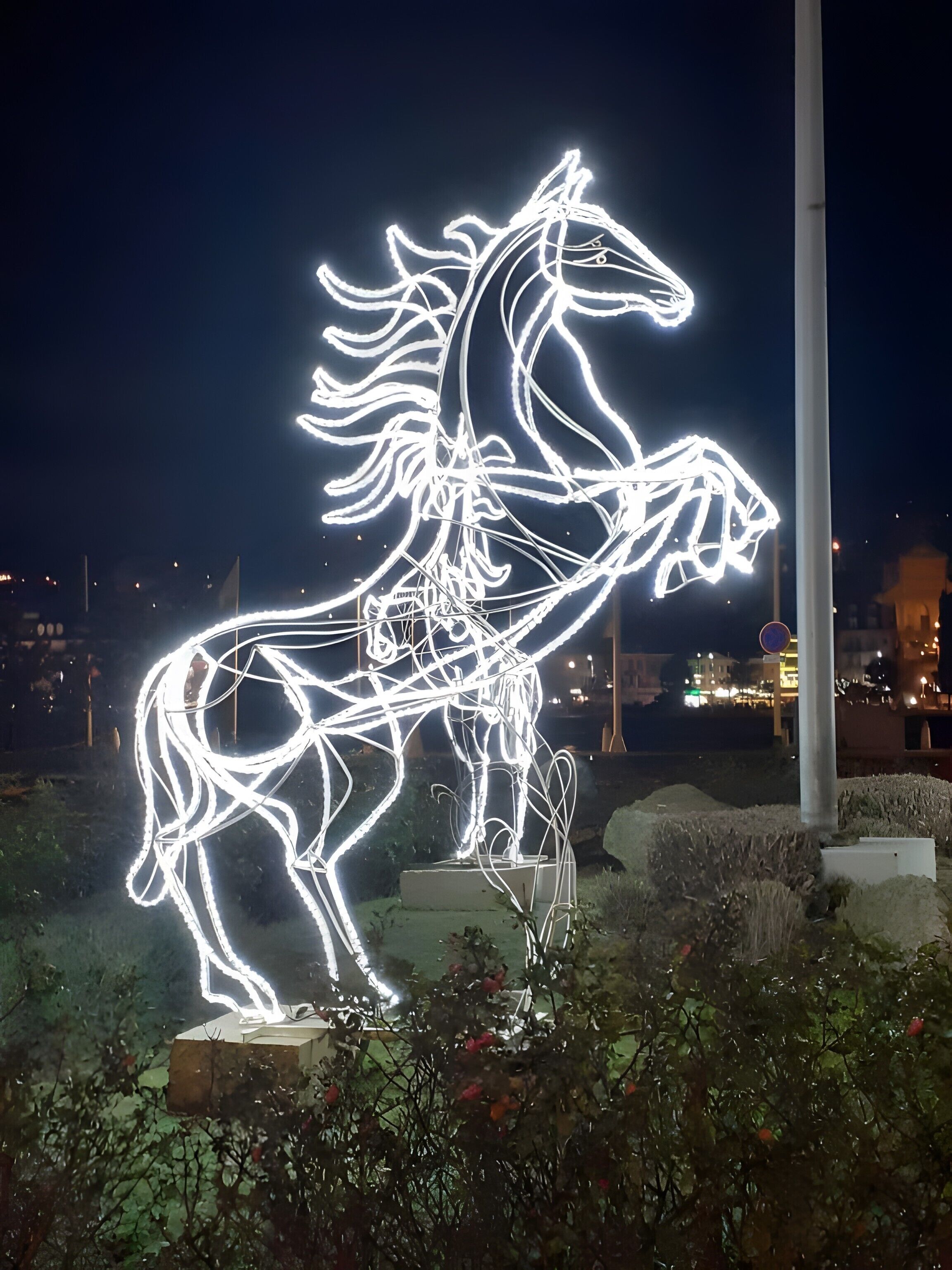 A nighttime illuminated sculpture of a horse.