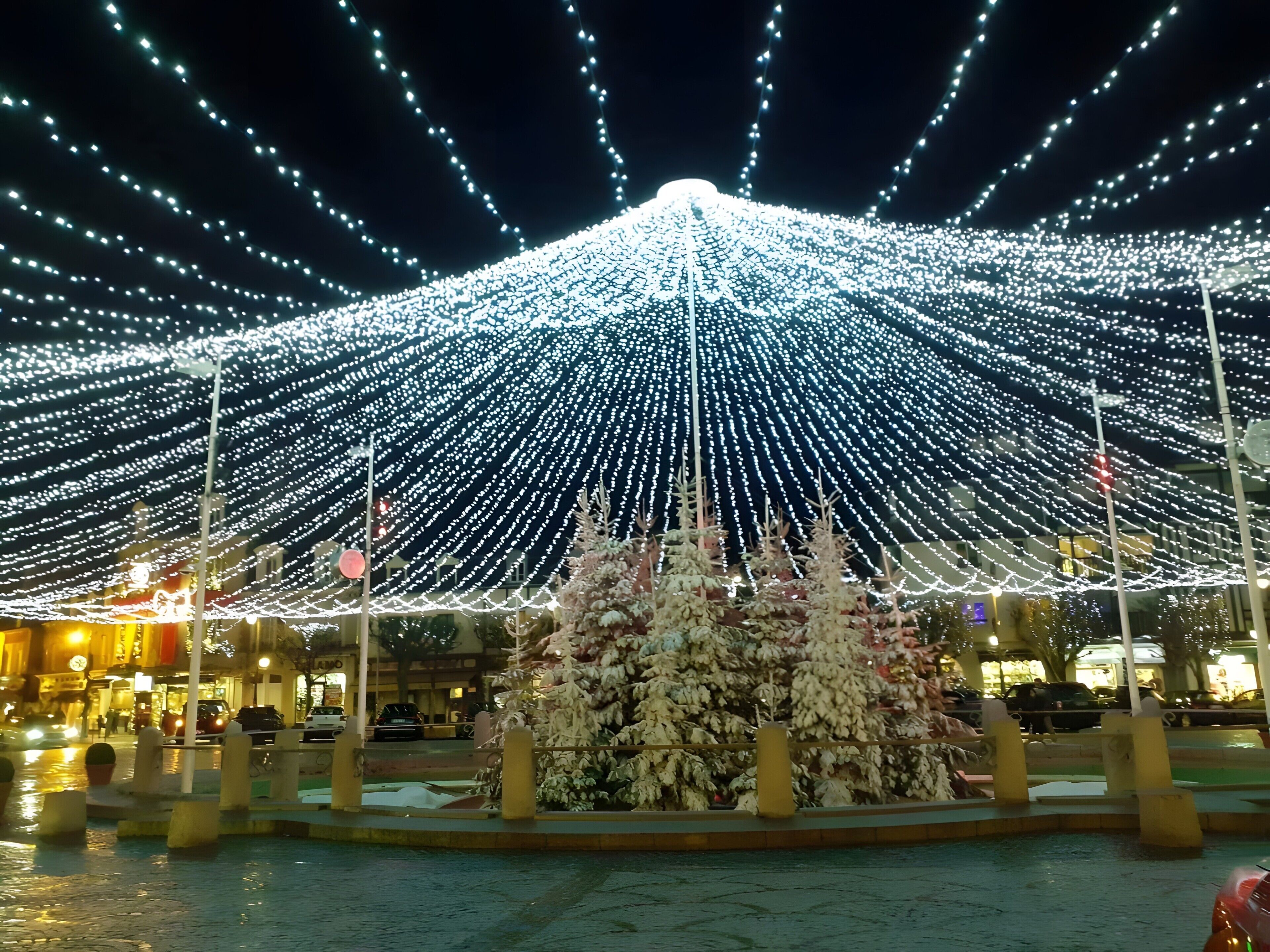 Ein Platz mit einem mit Schnee bedeckten Weihnachtsbaum und einer Lichterkette.