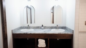Une salle de bain avec deux lavabos, un grand miroir et un porte-serviettes.