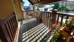 A wooden balcony with a railing, potted plants, and a view of buildings. - Le cottage d'Honfleur, apartment with parking! (Honfleur)