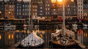 A harbor with sailboats docked, buildings in the background, and a sunset. - Le cottage d'Honfleur, apartment with parking! (Honfleur)