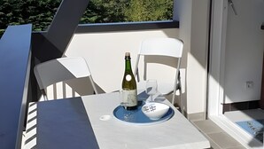 Ein Balkon mit Tisch, Stühlen, einer Weinflasche und einem Glas.