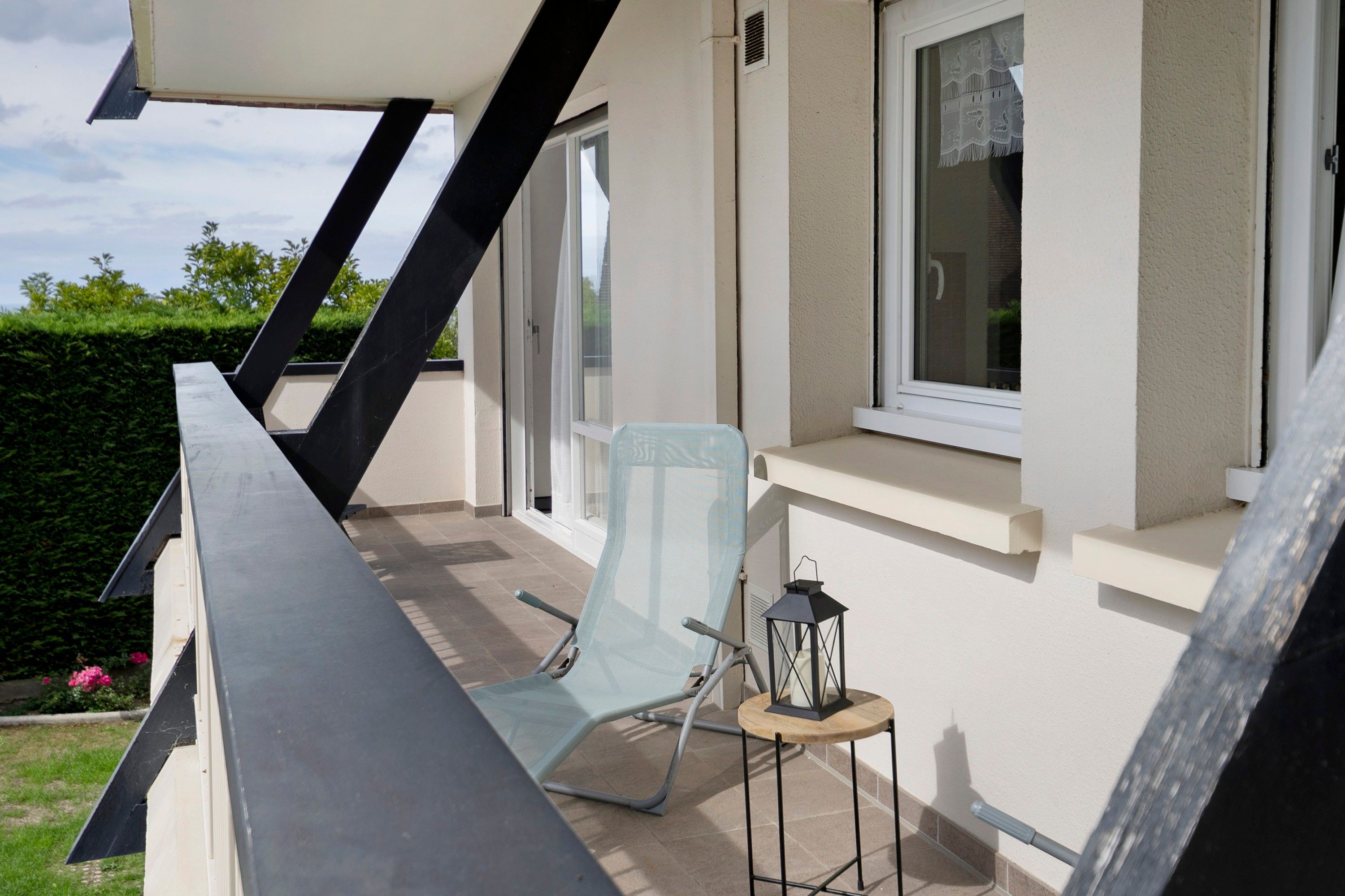 A balcony with a chair, a small table, and a lantern.
