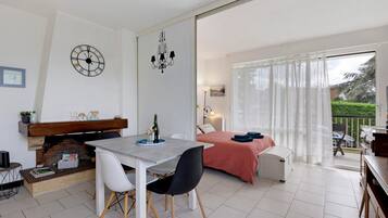 Et moderne soveværelse med seng, balkon med udsigt og spiseplads med bord og stole.