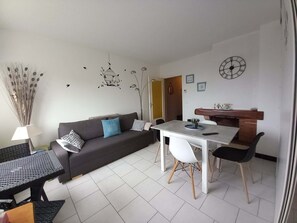Un salon moderne comprenant un canapé, une table à manger, des chaises et un coin cuisine.