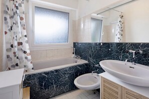 Une salle de bain moderne équipée d’une baignoire, d’un lavabo et d’un bidet.