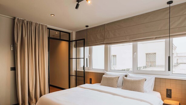 Ein Hotelzimmer mit einem großen Bett, einem Fenster mit Blick, einem Vorhang und einem Nachttisch.