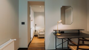 Ein Flur mit Heizkörper, Tisch, Stühlen, einer Lampe und einem Spiegel an der Wand.