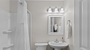 Een badkamer met toilet, wastafel en spiegel.