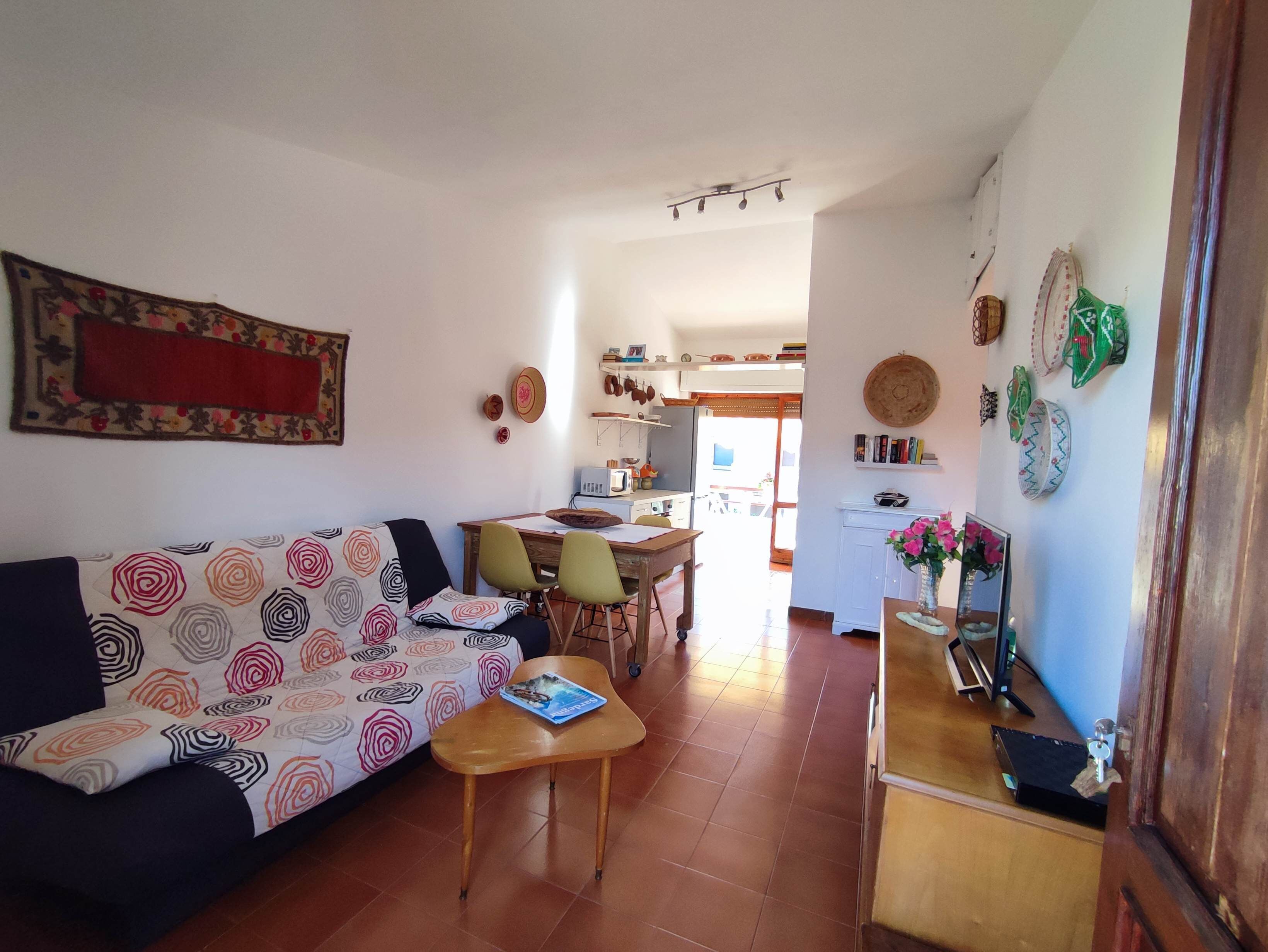 A cozy living room with a sofa, a wooden table, and a kitchen area in the background.