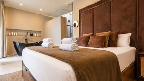 A modern hotel room with a large bed, a bathtub, and a separate bathroom. - Prado Suites Apartments (Málaga)