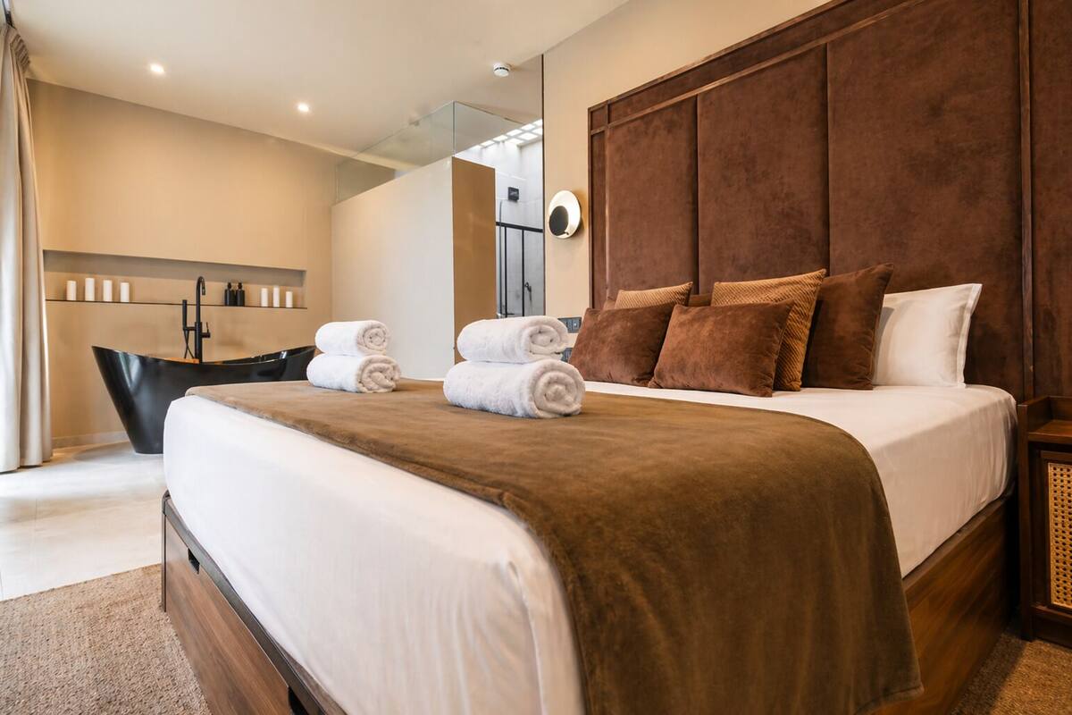 Ein modernes Hotelzimmer mit einem großen Bett, einer Badewanne und einem separaten Badezimmer.