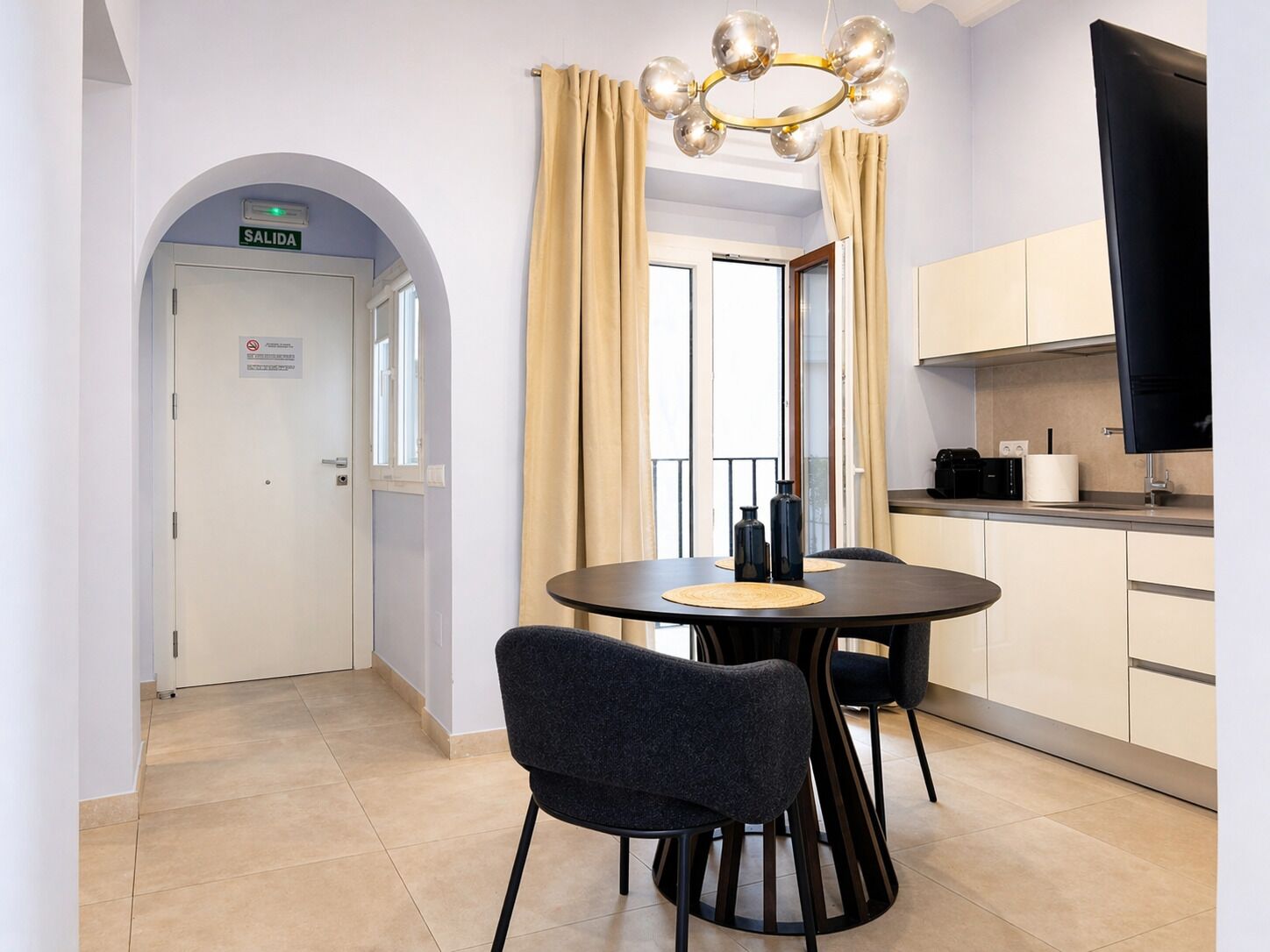 Una cucina moderna con zona pranzo, televisore e una porta con la scritta 'SALIDA'.